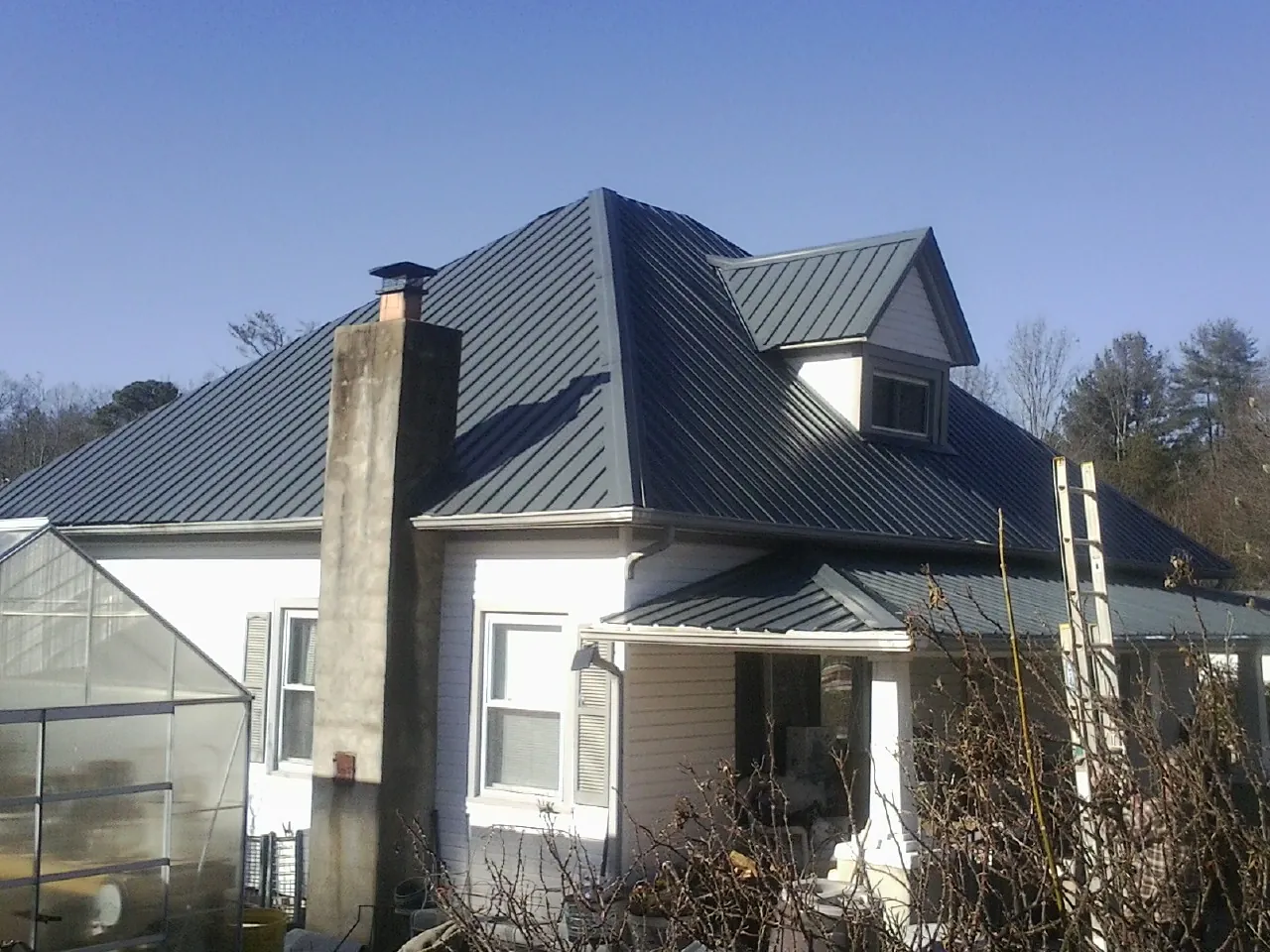Dark blue standing seam metal roof on a white farmhouse with dormer — Slate & Tile Roof Repair by Roofing Brothers in Loudon