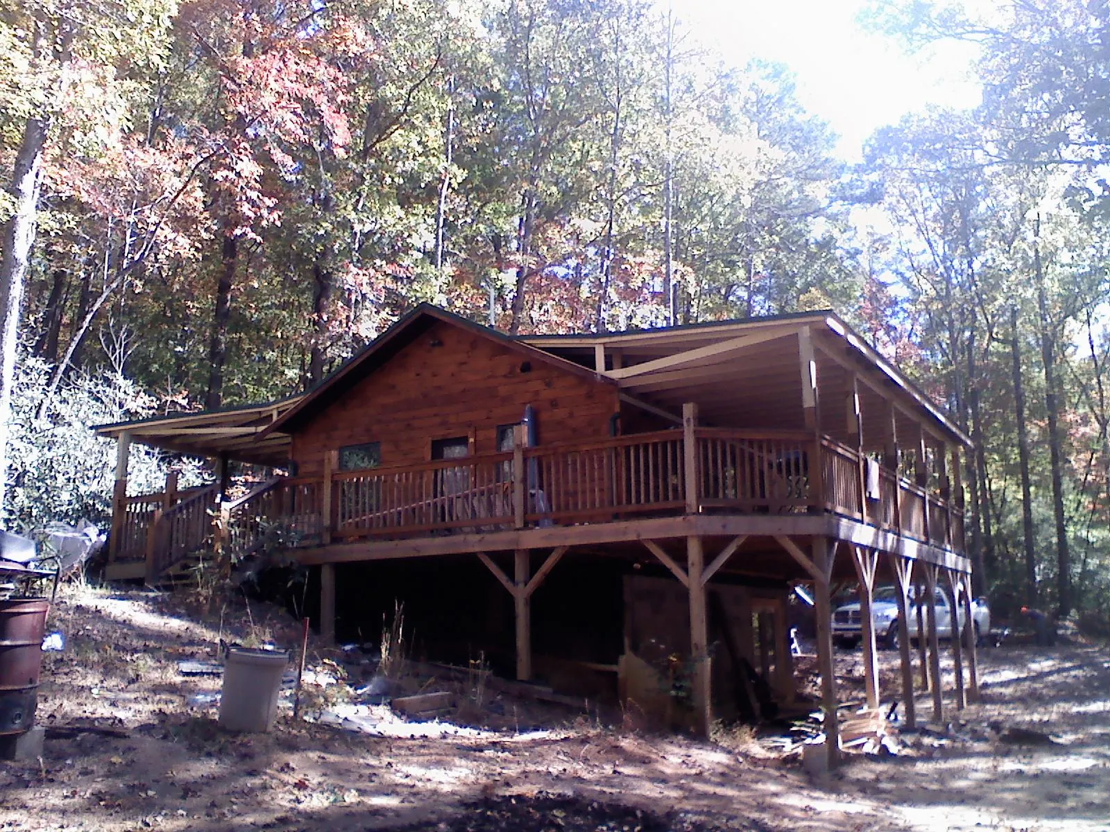 Log cabin with a wraparound porch and metal roof in the fall in Loudon