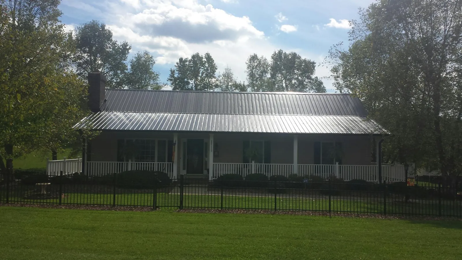 Gray metal roof on a brick ranch with a full width front porch — Gutter Guard Installation work by our crew in Loudon