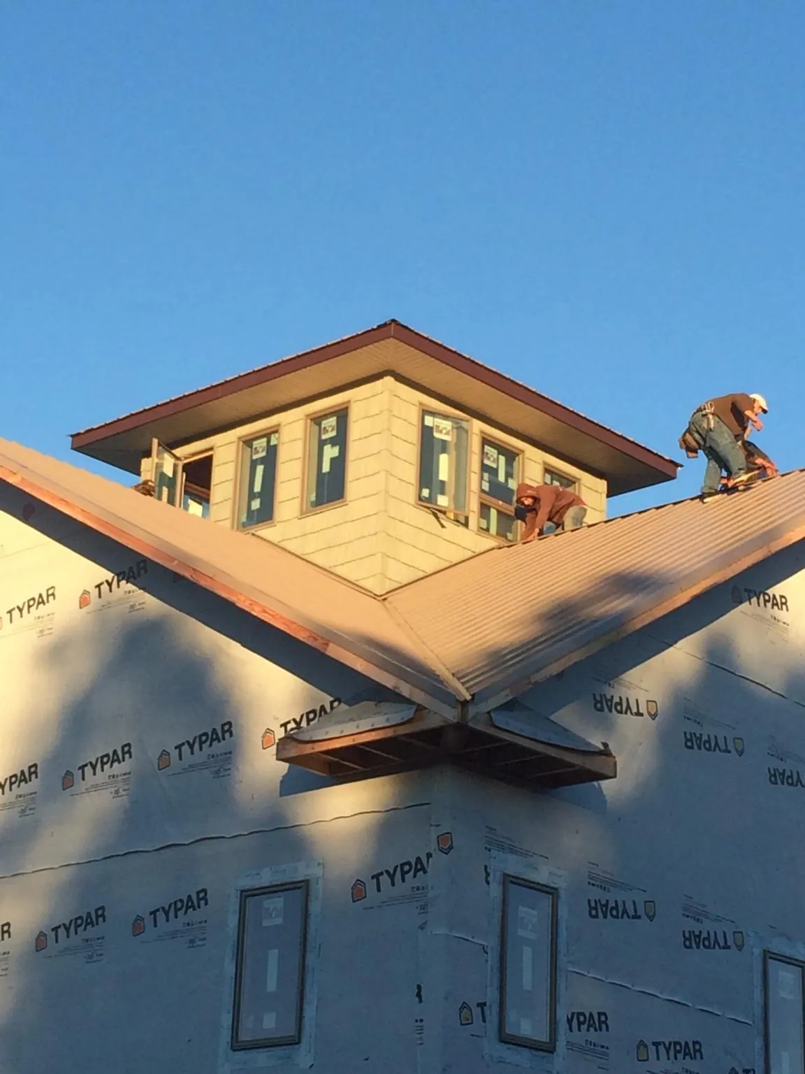 Roofers working around a rooftop cupola on a new metal roof at sunset — Roof Waterproofing in Loudon by Roofing Brothers